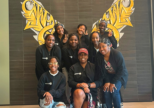 A group of students smiling with wings in the background.