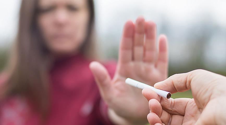 A female in the background rejects a cigarette.