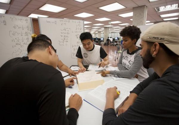 students gather around in library and share notes 