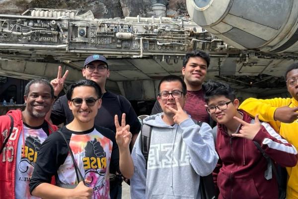 Seven men smiling in front of a mechanic ship.