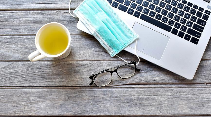 Laptop with surgical mask and a cup of tea